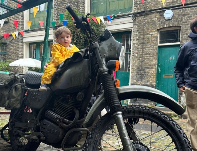 Beau in a yellow raincoat sitting on a motorbike